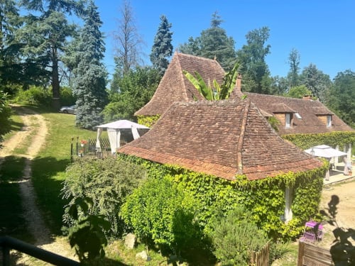 Charmante demeure en pierre avec toit de tuiles rouges au Domaine le Manoir à Fossemagne, entourée de jardins luxuriants