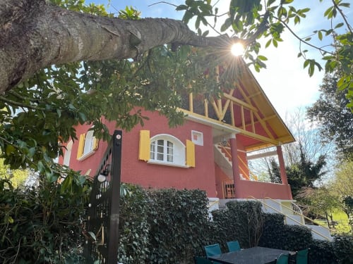 Charmant cottage en pierre rouge au Domaine le Manoir avec volets jaunes, entrée couverte de lierre et pergola en bois à Fossemagne