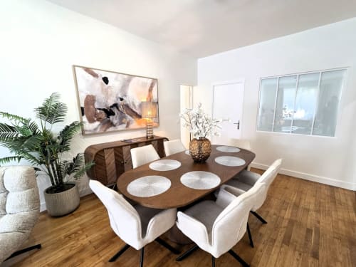 Salle à manger contemporaine dans un appartement de Levallois-Perret avec table en bois, chaises crème, plantes et œuvres d'art près de La Défense