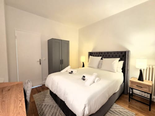 Chambre moderne avec lit queen-size, tête de lit noire et mobilier contemporain à l'appartement Conciergerie La Main d'Or