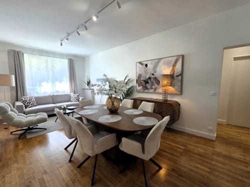Salle à manger moderne avec table en bois, chaises crème et espace salon à Levallois-Perret près de Paris