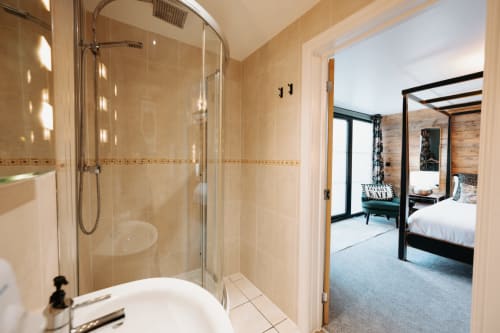 Modern bathroom with glass shower enclosure, white sink, and view into bedroom at Shrewsbury Rooms boutique hotel