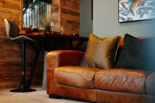 Luxury leather sofa with gold cushions in Deluxe King Suite at Shrewsbury boutique hotel, cognac armchair and desk visible