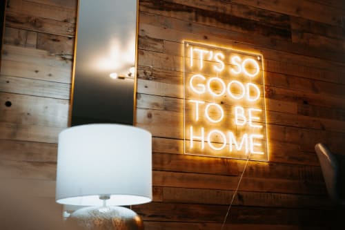 Neon sign reading 'It's So Good To Be Home' above white lamp in Shrewsbury boutique hotel room