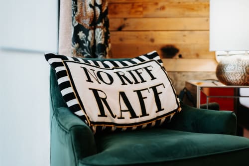 Green velvet armchair with decorative "Norriff Raff" pillow in Shrewsbury boutique hotel room's sitting area