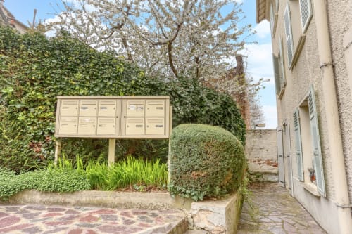 Vue du jardin à Queen and King Versailles avec boîtes aux lettres, haie de lierre et arbre fleuri près de Chaville