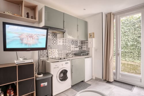 Kitchenette moderne avec lave-linge, électroménagers blancs, carrelage à motifs, TV et vue sur le jardin à l'hôtel Queen And King