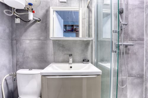 Salle de bains moderne de l'hôtel Queen And King à Versailles avec lavabo blanc, toilettes, douche et vue sur la fenêtre
