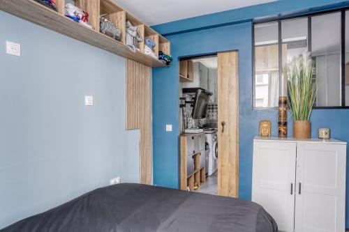 Chambre moderne à l'hôtel Queen And King, Chaville avec murs bleus, rangements blancs, accents en bois et accès à buanderie