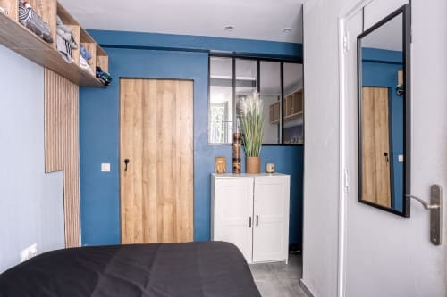 Chambre moderne de l'hôtel Queen And King à Chaville près de Versailles, avec mur d'accent bleu, portes en bois, rangements blancs et