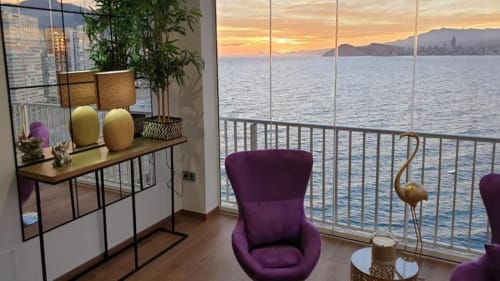 Vista al atardecer del Mediterráneo desde Portofino Playa Apartamentos en Benidorm con silla morada y decoración moderna