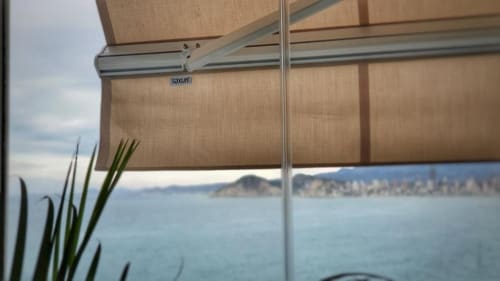 Persiana enrollable beige con vista al océano y ciudad costera desde el balcón de Portofino Playa en Benidorm