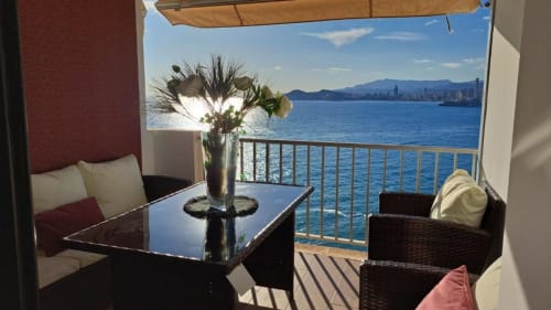 Balcón con vistas al mar en Portofino Playa, Benidorm con mesa, flores y costa mediterránea