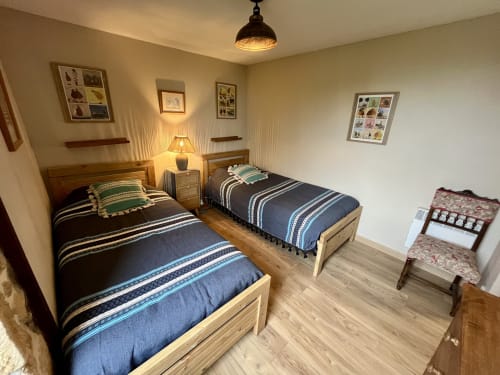 Chambre douillette au Gîte La Vieille Ferme de La Doinie à Saint-Geniès avec lits jumeaux, mobilier en bois et éclairage chaleureux