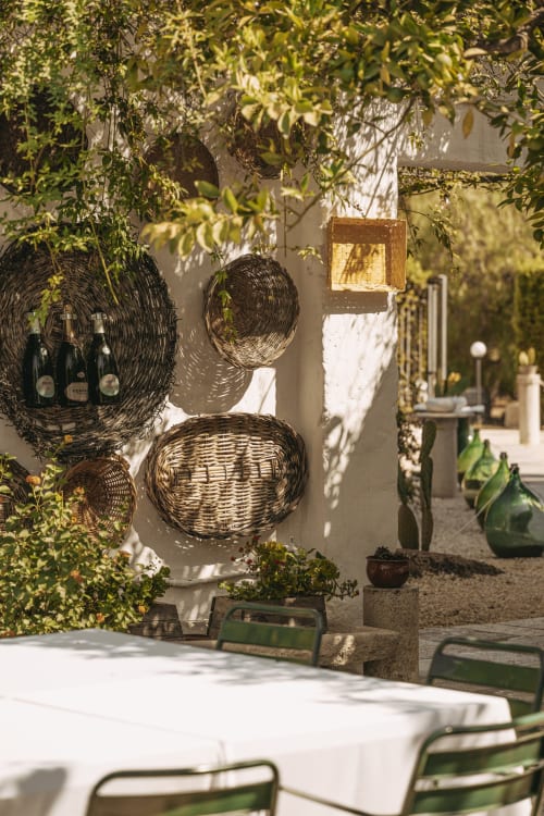 Cortile di Villa Ceci ad Andria con cesti intrecciati, edera, tovaglia bianca e sedie verdi