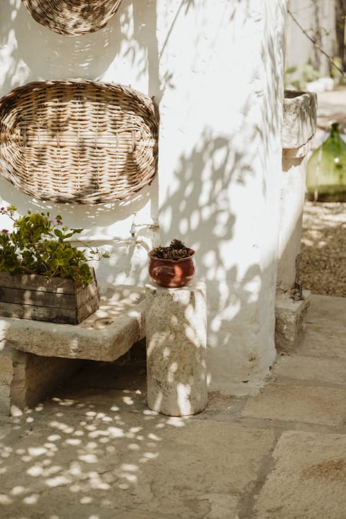 Cortile rustico di Villa Ceci ad Andria con cesti intrecciati, piante in vaso e luce screziata su muri imbiancati