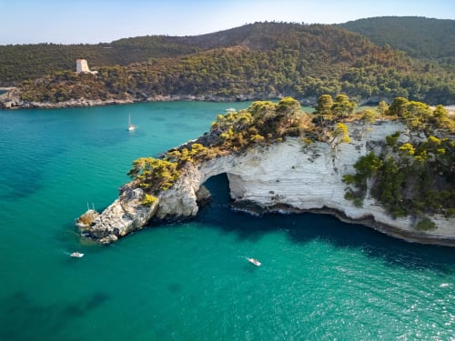 Insenatura turchese con scogliere calcaree bianche, barche a vela e colline boscose presso Villa Ceci ad Andria, Italia