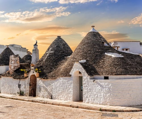 Tradizionali case trulli in pietra con tetti conici di Villa Ceci bed and breakfast ad Andria, Italia al tramonto
