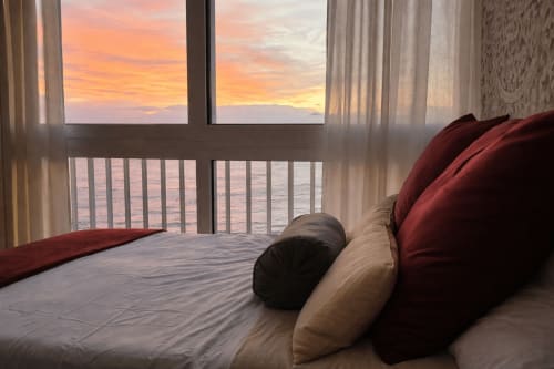 Vista al atardecer desde la habitación de Portofino Playa en Benidorm con vistas al mar, balcón y almohadas rojas