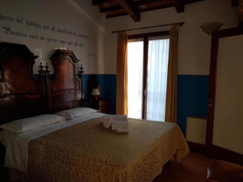 Camera tripla a Agriturismo Villa Mocenigo a Mirano con letto, travi in legno, pareti azzurre e porte-finestre sulla proprietà