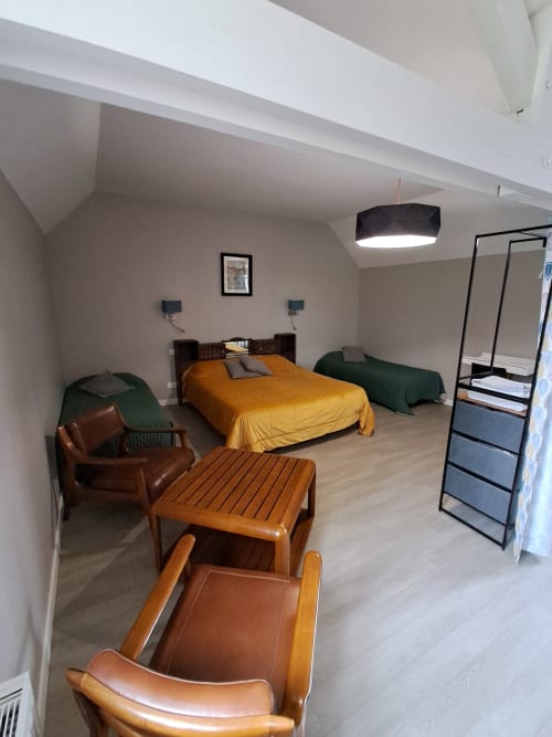 Spacieuse chambre familiale au Domaine De Bertheauville avec lit queen-size, coin salon, mobilier en bois et éclairage moderne