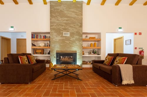 Lounge moderno com lareira, sofás marrom e vigas de madeira na Cerro da Campaniça B&B em Santiago do Cacém