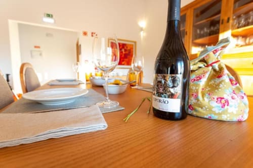 Mesa de jantar elegantemente arrumada na Pousada Cerro da Campaniça em Santiago do Cacém, com garrafa de vinho e talheres