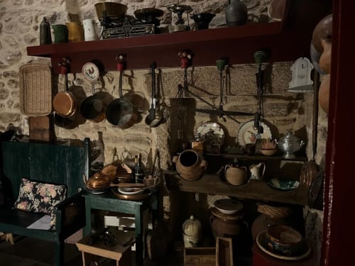Rustic kitchen display at Portuguese quinta with copper pans, pottery, and traditional cookware on stone walls