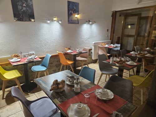Salle à manger du petit-déjeuner de l'Auberge Du Campcardos à Porta avec chaises colorées, tables dressées et murs texturés blancs