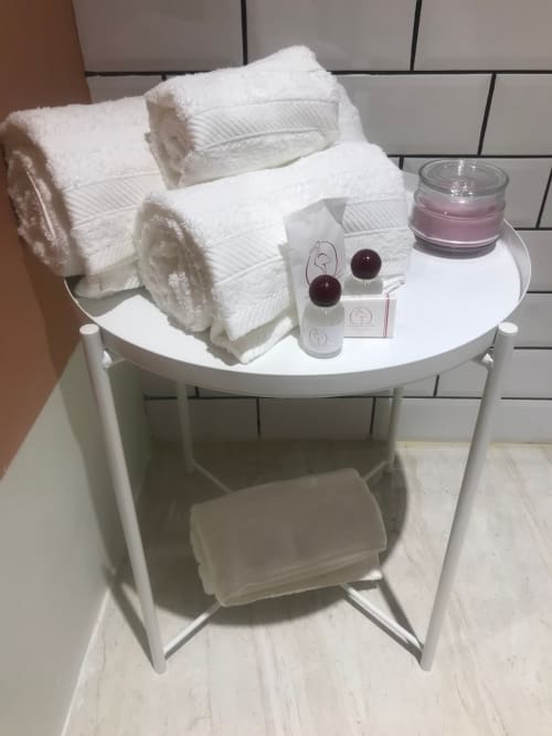 Elegante allestimento di amenities da bagno su tavolo rotondo con asciugamani arrotolati, candele e prodotti per l'igiene al Tresette Toledo Napoli
