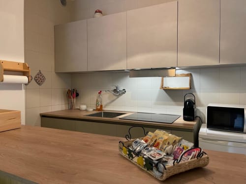 Cucina moderna nell'appartamento LHE Alba a Cesena con pensili bianchi, piano in legno, piano cottura a induzione e ripostigli organizzati