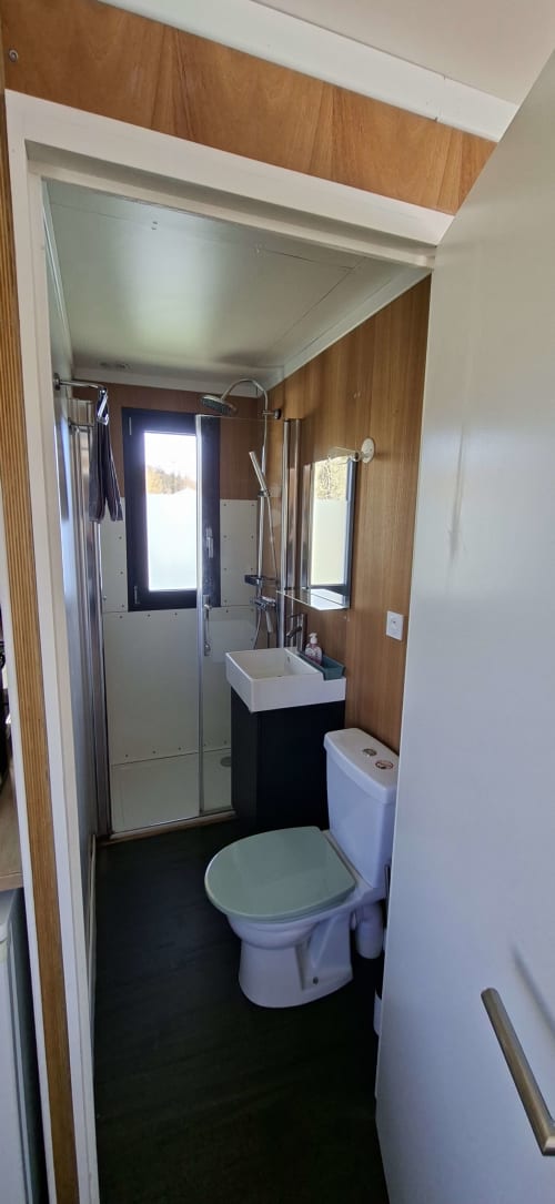 Modernes Badezimmer der Wohnung Le Lodge im Domaine Saône-Valley mit Dusche, Waschbecken, Toilette und Holzakzenten