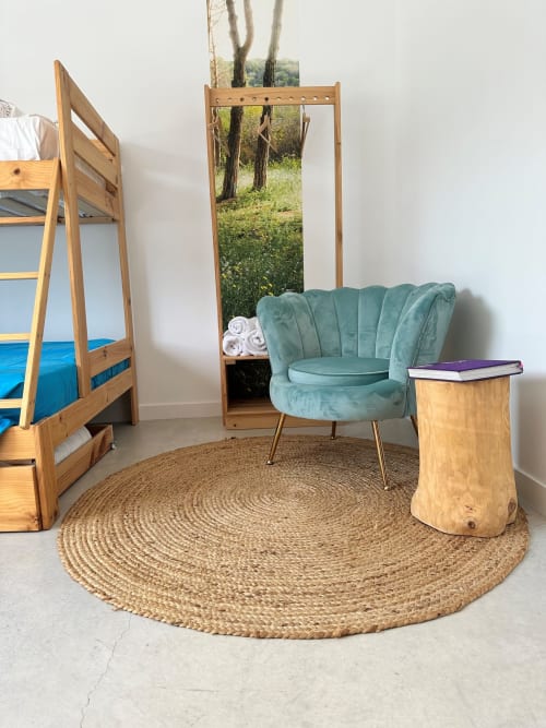 Acogedora habitación en Entheos Rural con sillón de terciopelo turquesa, cama litera de madera y alfombra redonda natural en Lerín
