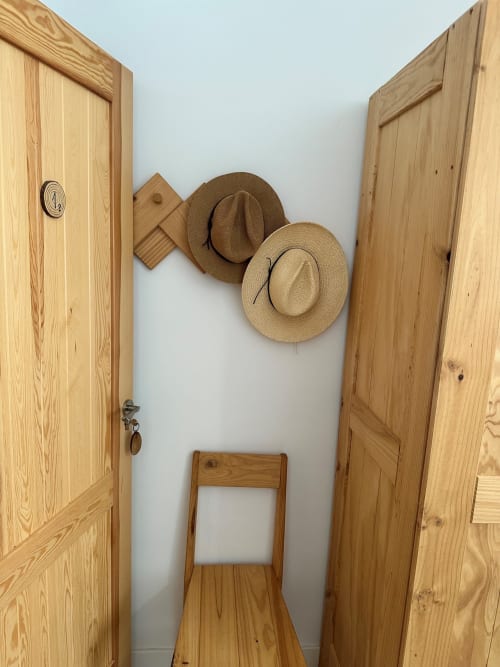 Pasillo de madera entre dos puertas en Entheos Rural con sombreros vaqueros en pared blanca y silla de madera, Lerín España