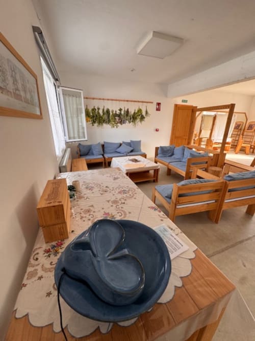 Salón comunitario de Entheos Rural en Lerín con muebles de madera, cojines azules, decoración con hierbas secas y vistas a la montaña