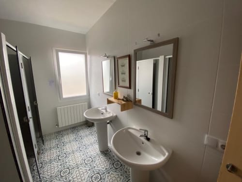 Baño moderno en Entheos Rural con lavabos dobles, espejos y piso de azulejos decorativos en Lerín