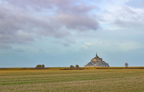 Mont Saint-Michel castle rising from vast green fields near La Bergerie De Montitier in Huisnes-sur-Mer, France