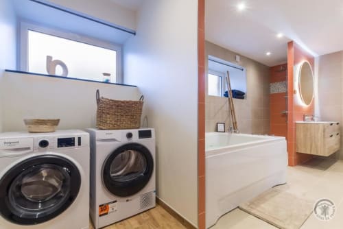 Modern laundry and bathroom area at La Bergerie De Montitier cottage in Huisnes-sur-Mer with washer, dryer, bathtub and