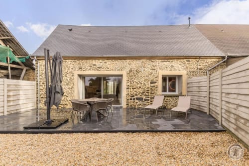 Garden view patio at La Bergerie De Montitier cottage in Huisnes-sur-Mer with stone facade, loungers, and umbrella