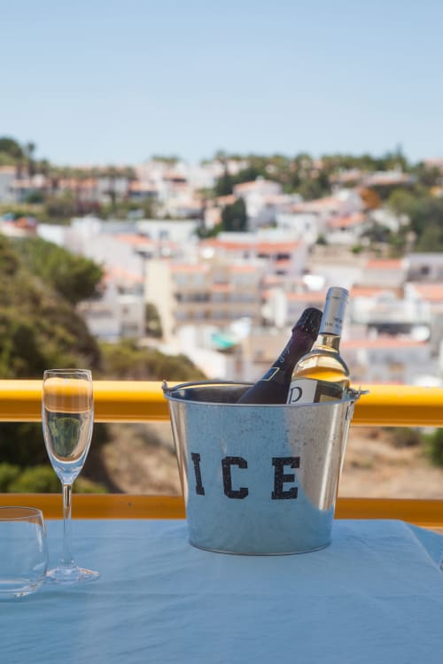 Champagne chilling in ice bucket on terrace overlooking Lagoa, Portugal with coastal town view