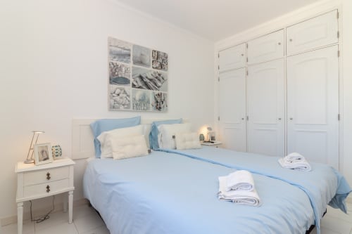 Modern bedroom at MarVillas Rentals Casa Branco in Lagoa with light blue bedding, white furnishings, and built-in wardrobe