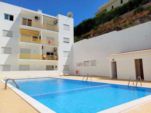 Swimming pool at MarVillas Rentals Casa Branco apartment in Lagoa, Portugal with white buildings and yellow balconies