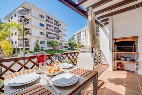 Terraço exterior do AlgarStays em Silves com mesa de jantar, guarda-sol, lareira e vista para o apartamento