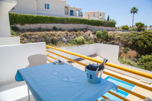 Mesa azul na varanda da MarVillas Rentals em Lagoa, Portugal com vista para a encosta e vilas brancas