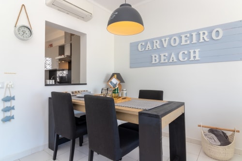 Interior do escritório de aluguel da Praia do Carvoeiro com secretária, cadeiras pretas, luminária pendente e decoração costeira na propriedade MarVillas Lagoa.
