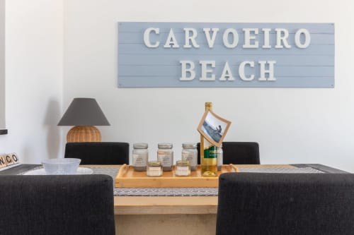 Placa de Praia de Carvoeiro acima da mesa de jantar com cadeiras pretas e serviço de vinho na MarVillas Rentals em Lagoa, Portugal