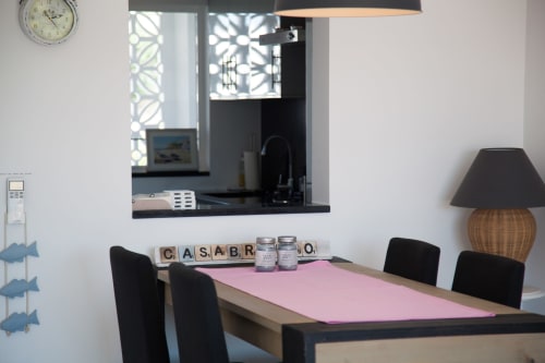 Área de jantar moderna em MarVillas Rentals em Lagoa com mesa rosa, cadeiras pretas e vista para a janela da cozinha