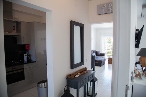 Entrada moderna da MarVillas Rentals em Lagoa com espelho de moldura preta, console cinzento e vista para a cozinha aberta