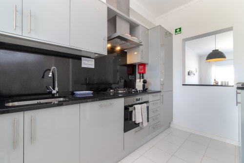 Cozinha moderna com armários brancos, bancadas e eletrodomésticos pretos em MarVillas Rentals, Lagoa, Portugal