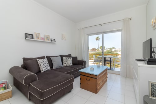 Sala de estar moderna com sofá escuro, mesa de madeira e vistas de varanda nas Vilas de Mar, Lagoa, Portugal
